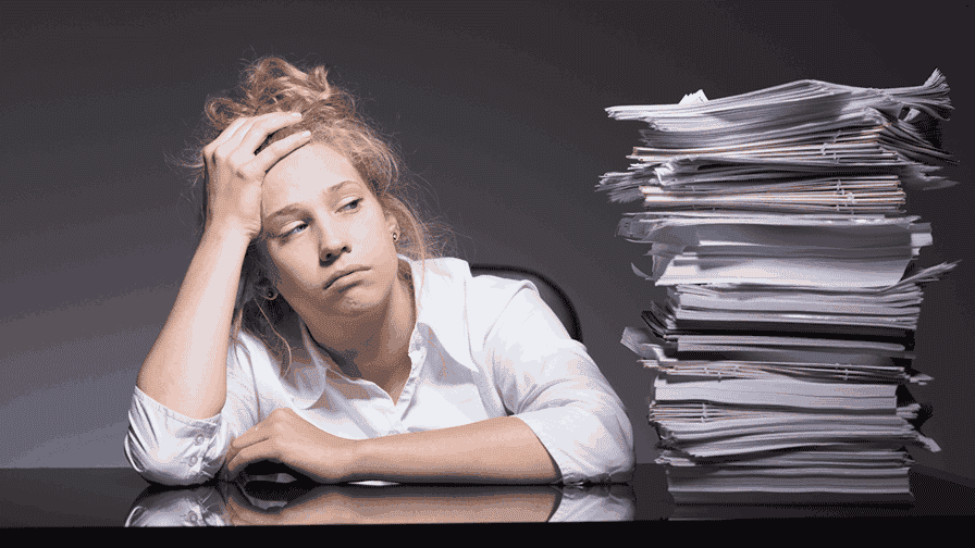 Woman stressed sitting next to a pile of tasks